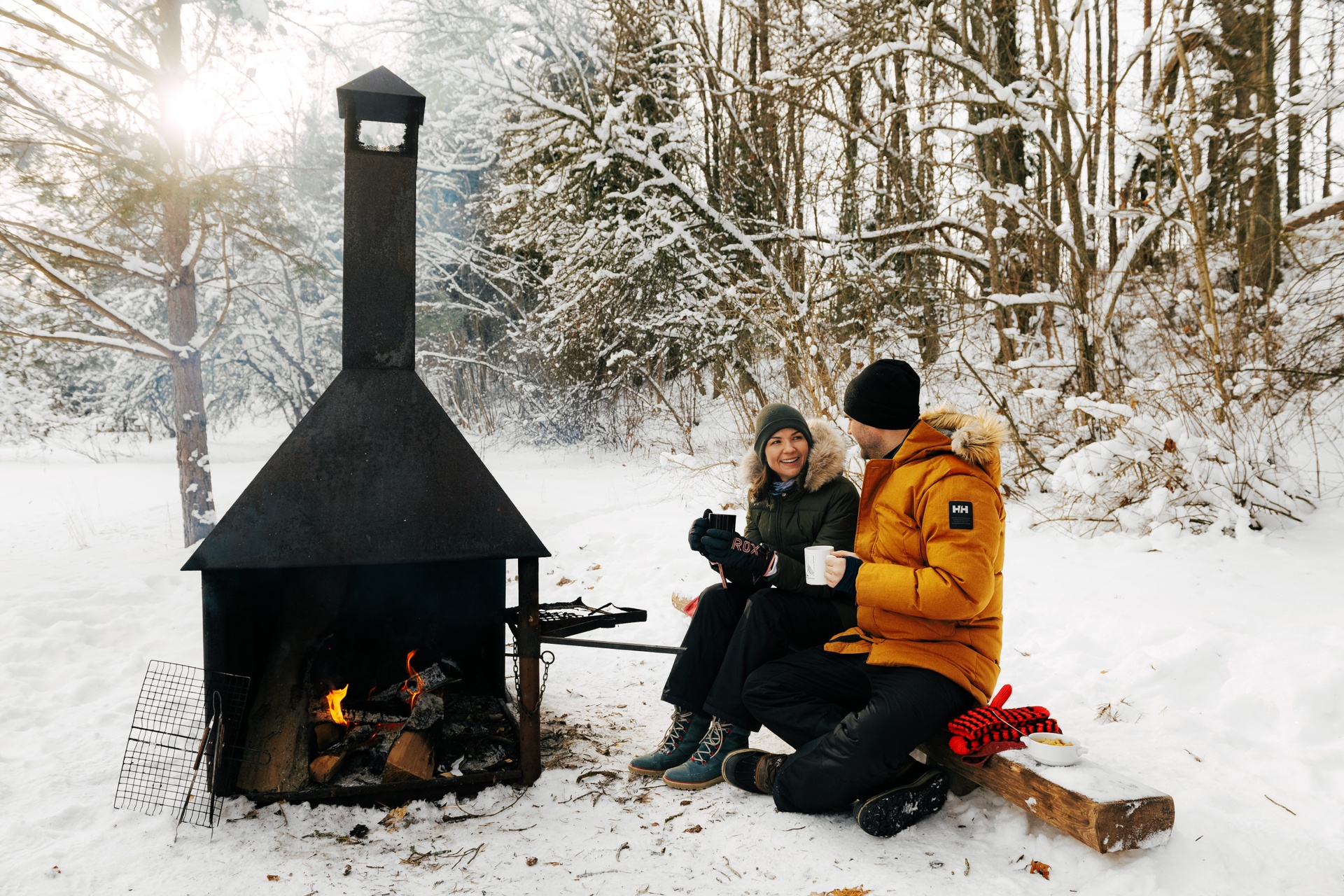 Two hikers warm up with a fire after a winter hike